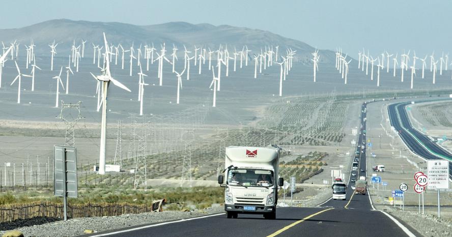 Vehicles pass by a wind farm in Xinjiang Uygur autonomous region.